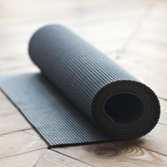 PVC Yoga Mat - Rolled up fitness mat on wooden floor at yoga studio