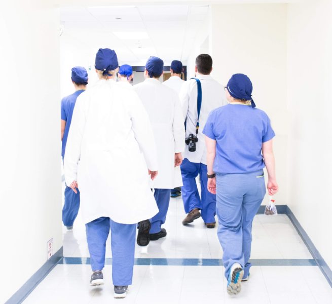  A group of healthcare workers walking down a hall in a hospital 