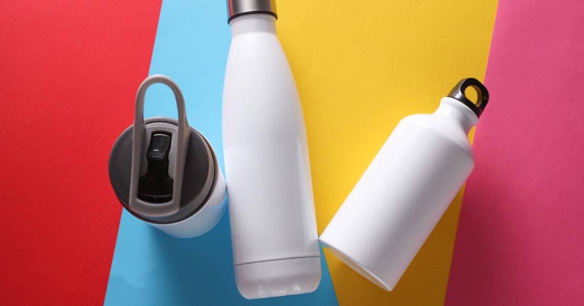 Three plain white water bottles of different sizes and types sit on a colorful backdrop with blue, yellow, and red stripes.