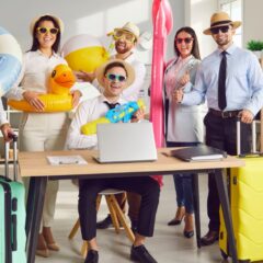 A group of office employees gathered around a workstation They all have custom sunglasses and other summer items