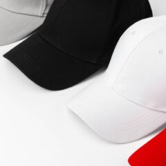 Four baseball caps sit on a white background They are red white gray and black and need customization