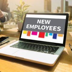 A computer on a work station with new employees typed on the screen There are colored labels at the screens bottom