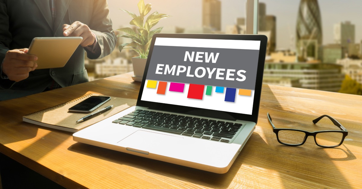 A computer on a work station with "new employees" typed on the screen. There are colored labels at the screen's bottom.
