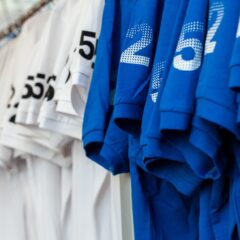 A long line of promotional T-shirts in colors blue red and white The sleeves on each shirt have a custom print