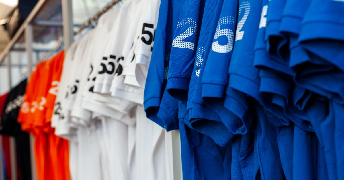 A long line of promotional T-shirts in colors blue, red, and white. The sleeves on each shirt have a custom print.