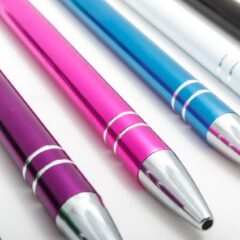 A close-up of a collection of ink pens They are metal metallic in a variety of colors green purple pink and blue