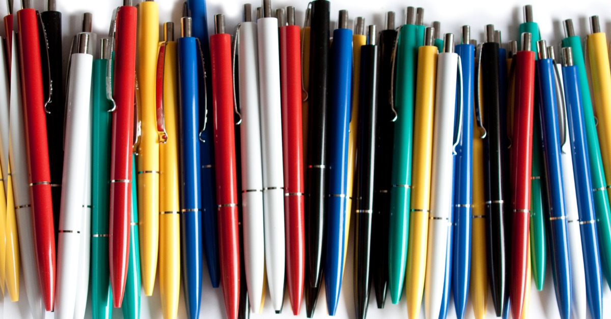 A collection of ink pens in a variety of different colors, including red, yellow, white, black, and blue.